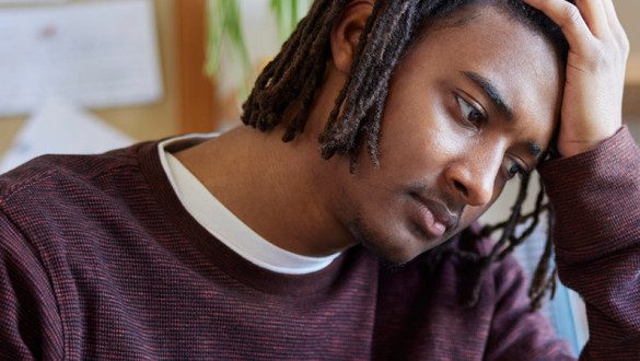 Male student looking frustrated with head in his hand.