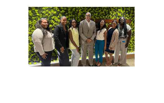 A group of people standing in front of a wall of foliage