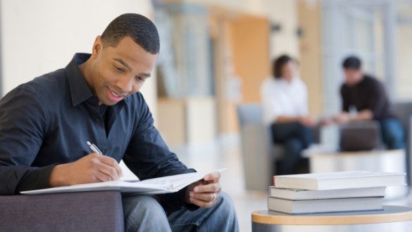 Guy sitting in chair writing in notebook