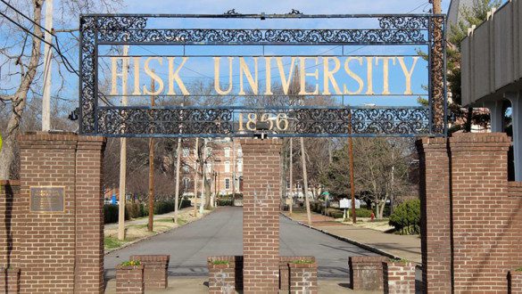 Fisk University is a historically Black university in Nashville, Tennessee. This image shows a gate with Fisk University letters above it, and brick buildings surrounding.