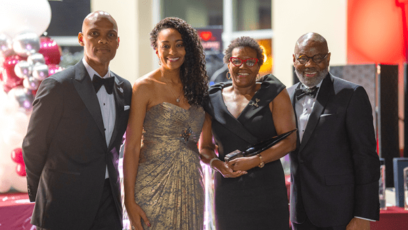 Four people posing together at the Higher Education Leadership Foundation awards