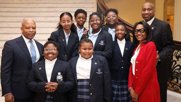 A small group of attendees posed as a group in front of a regal staircase