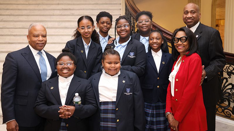 A small group of attendees posed as a group in front of a regal staircase