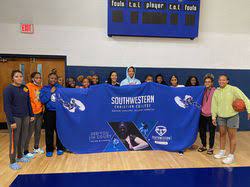 Students stand in a gymnasium holding a blue Southwestern Christian College banner