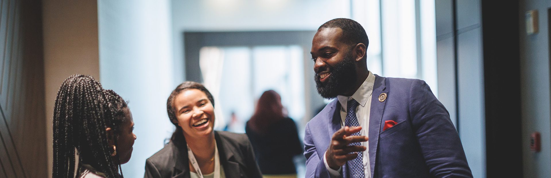 Three people in business attire interacting in a hallway