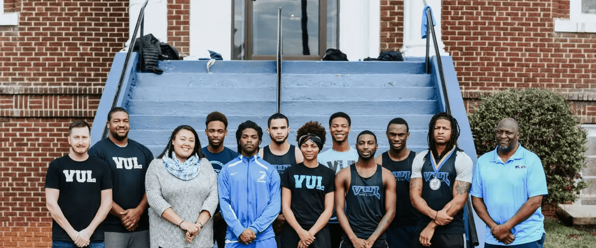 A group of students wearing VUL pose in front of a blue staircase.