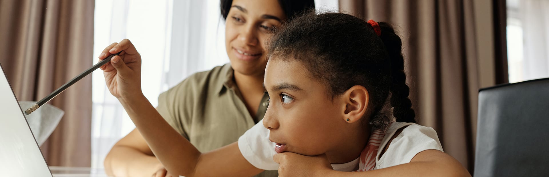 Young child and her mother doing homework on laptop