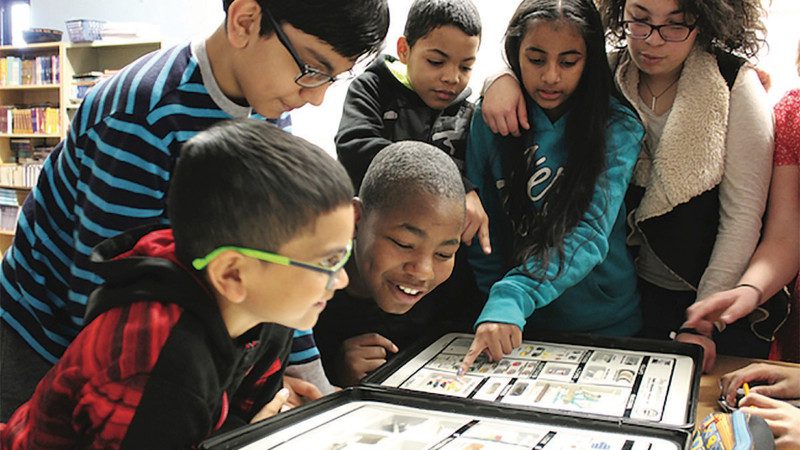 Group of kids pointing looking at a book