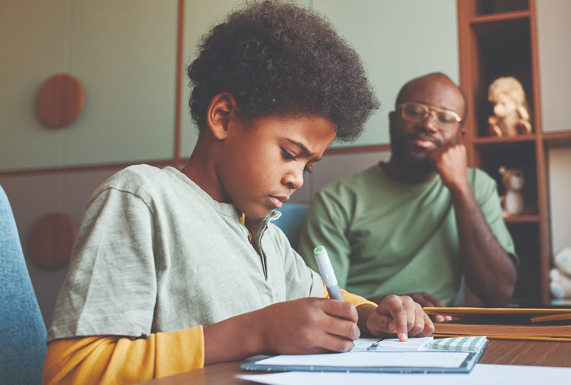 Student working on homework supervised by father