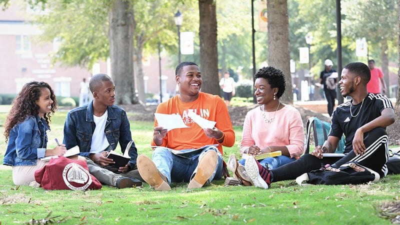 5 Claflin University students sitting on grassy campus outdoors