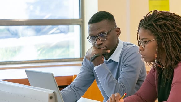 Two students working on laptops on campus library