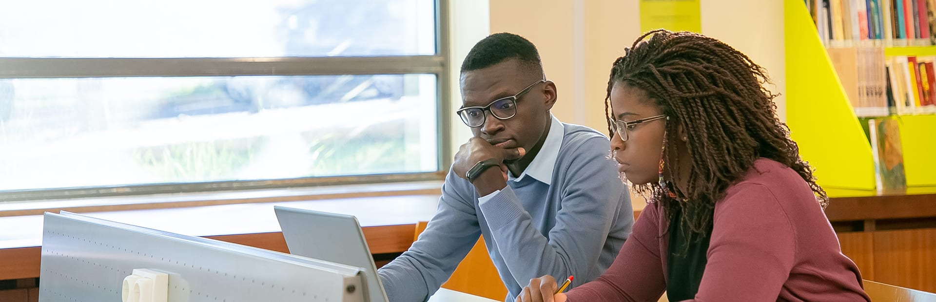 Two students working on laptops on campus library