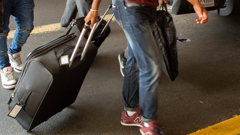Suitcase being rolled through airport by man