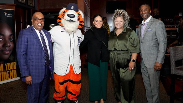 A group of five people posed together, one wearing a mascot costume