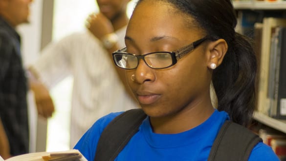 A female Voorhees student reads a book in the campus library