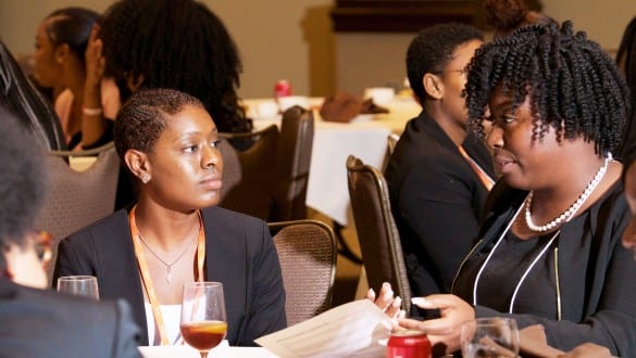 2 female Walton fellows conference attendees talking during group sessions